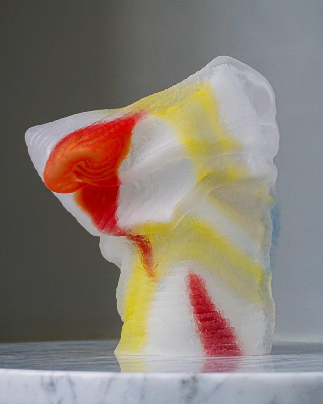 A prize sculpture for Utmärkt Svensk Form: frosted glass striped in rag-rug red and yellow on a marble plinth.