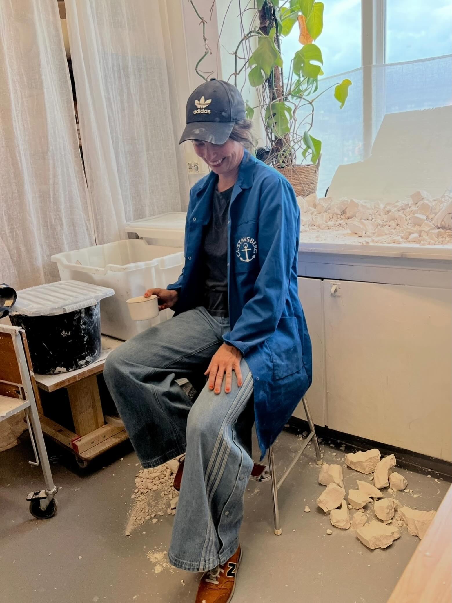 The artist seated in the studio among broken plaster pieces.